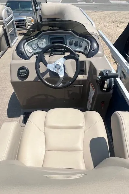 Slide: The Image of 2021 Sun Tracker Party Barge 20 DLX helm with beige seating and modern dashboard controls. - 4