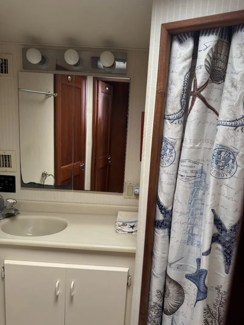 Slide: The Image of Bathroom interior of a 1989 Viking 45 Convertible yacht with nautical-themed shower curtain. - 17