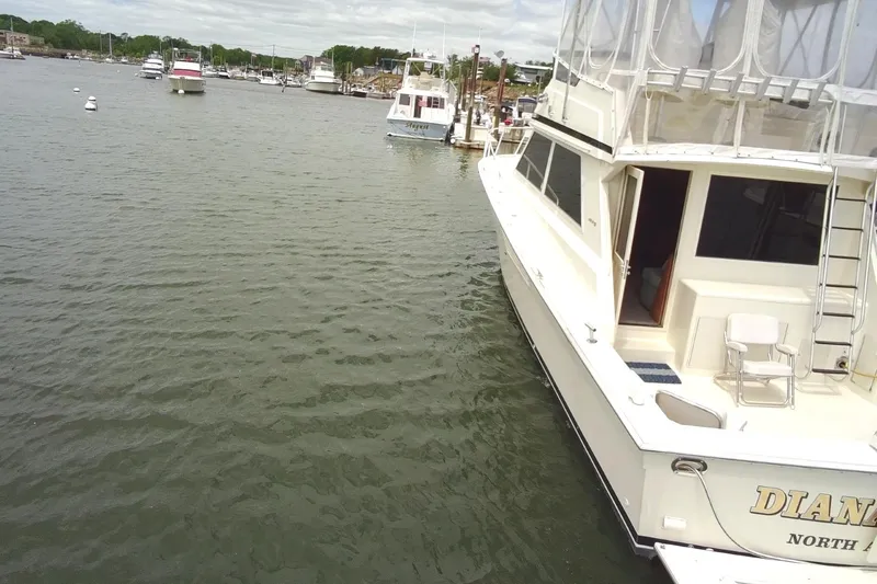 Slide: The Image of 1989 Viking 45 Convertible yacht docked in a marina, surrounded by calm waters and other boats. - 3
