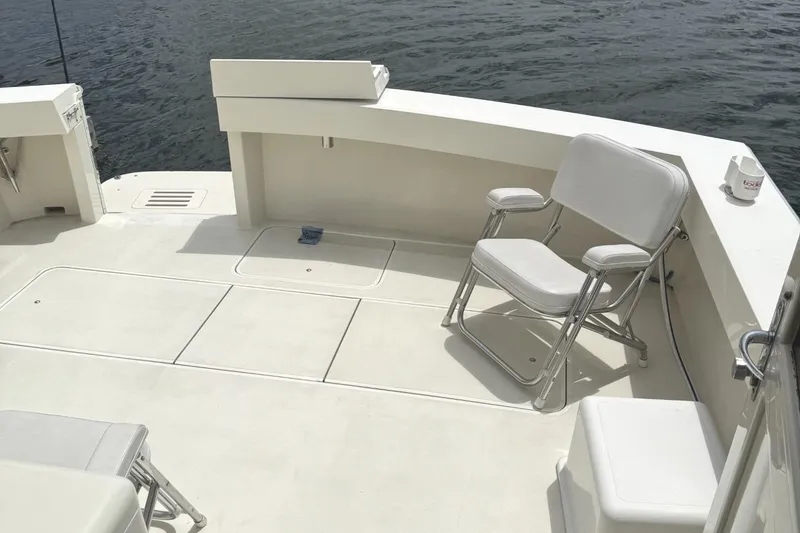 Slide: The Image of 1989 Viking 45 Convertible boat deck with white seating and calm water backdrop. - 32