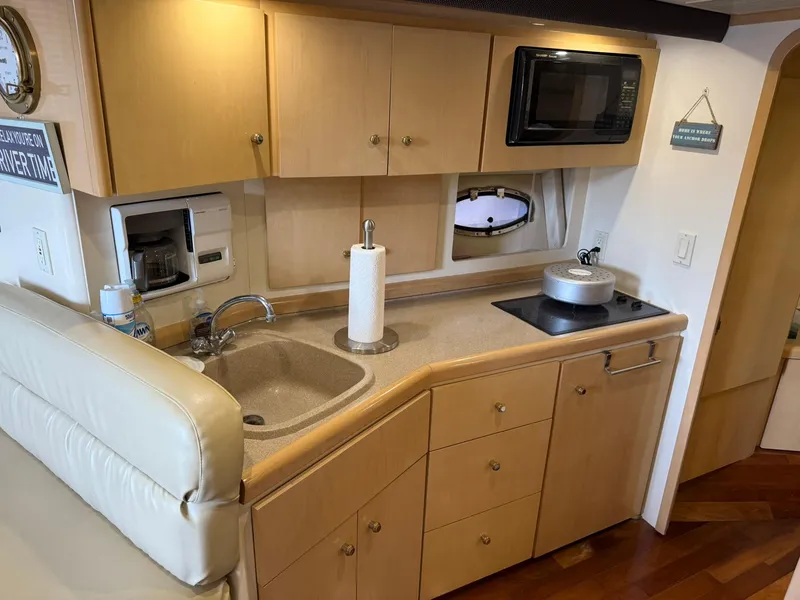 Slide: The Image of 2000 Carver 350 Mariner kitchen with sink, stove, microwave, and wooden cabinets. - 23