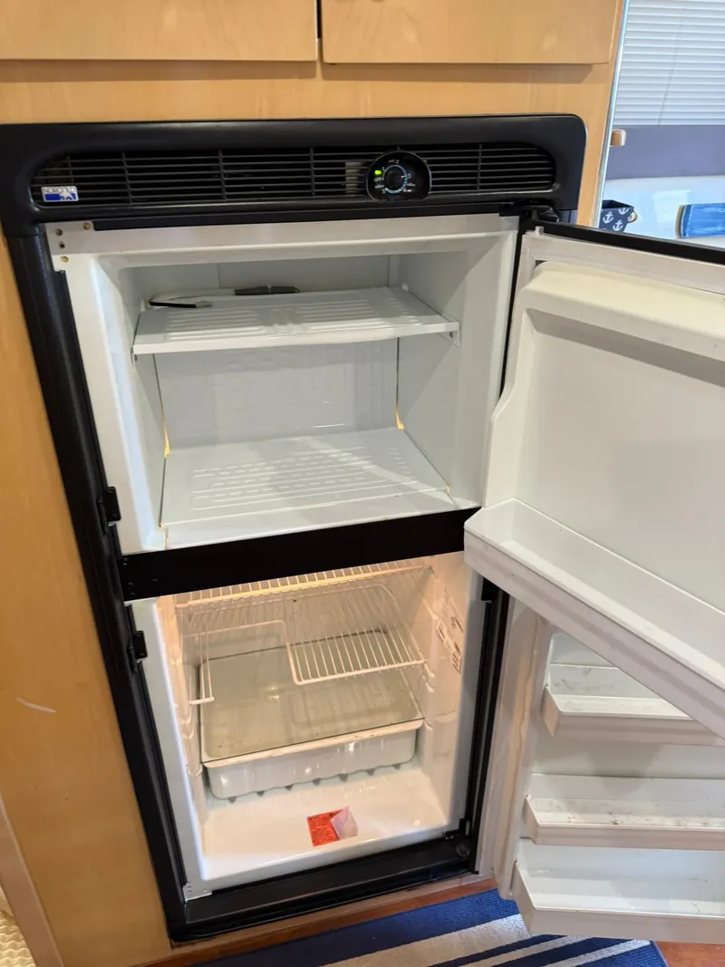 Slide: The Image of Open refrigerator inside a 2000 Carver 350 Mariner boat, showing empty shelves and door compartments. - 28