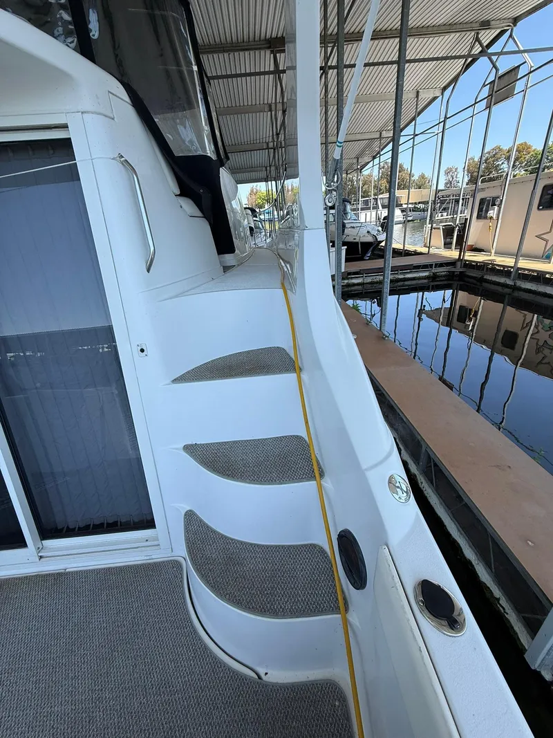 Slide: The Image of 2000 Carver 350 Mariner yacht docked, showcasing side deck and steps under a covered marina. - 5