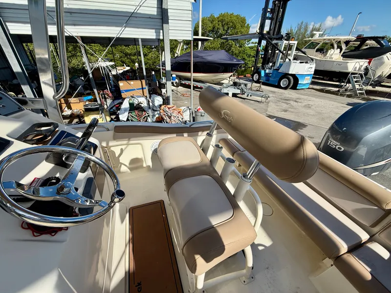 Slide: The Image of 2012 Scout 210 XSF boat interior with steering wheel and seating, docked near other boats. - 2