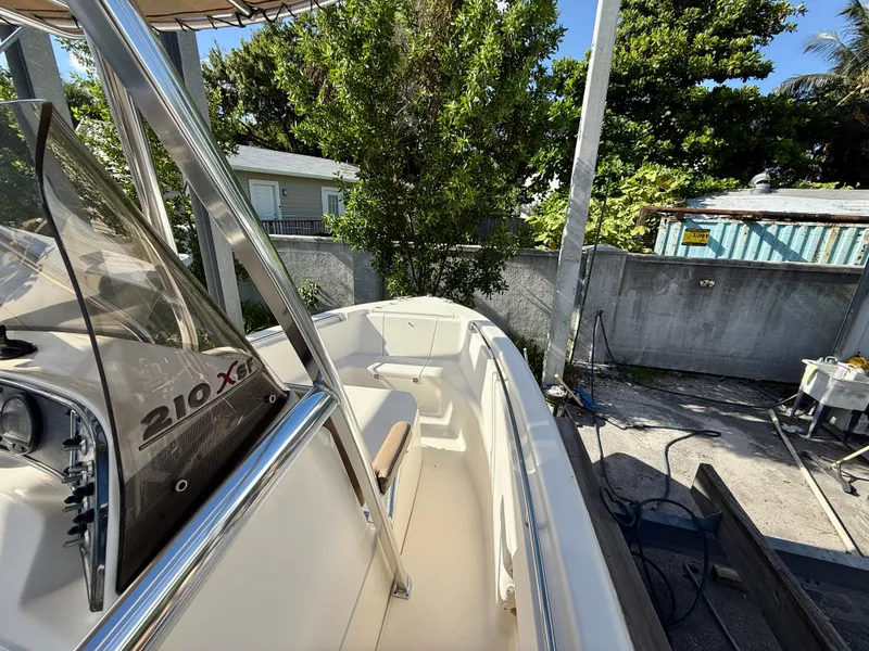 Slide: The Image of 2012 Scout 210 XSF boat docked, surrounded by trees and a concrete wall. - 9