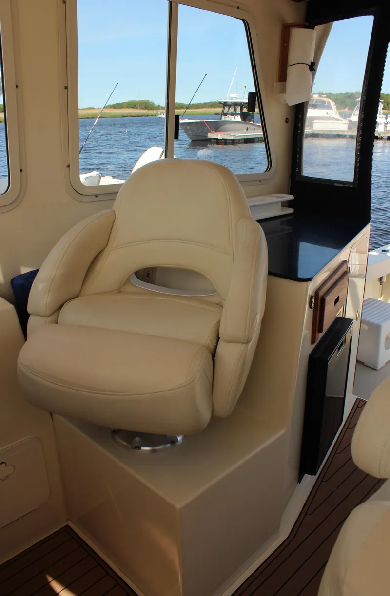 Slide: The Image of 2016 Eastern 27' Islander boat interior with beige captain's chair and scenic water view. - 21