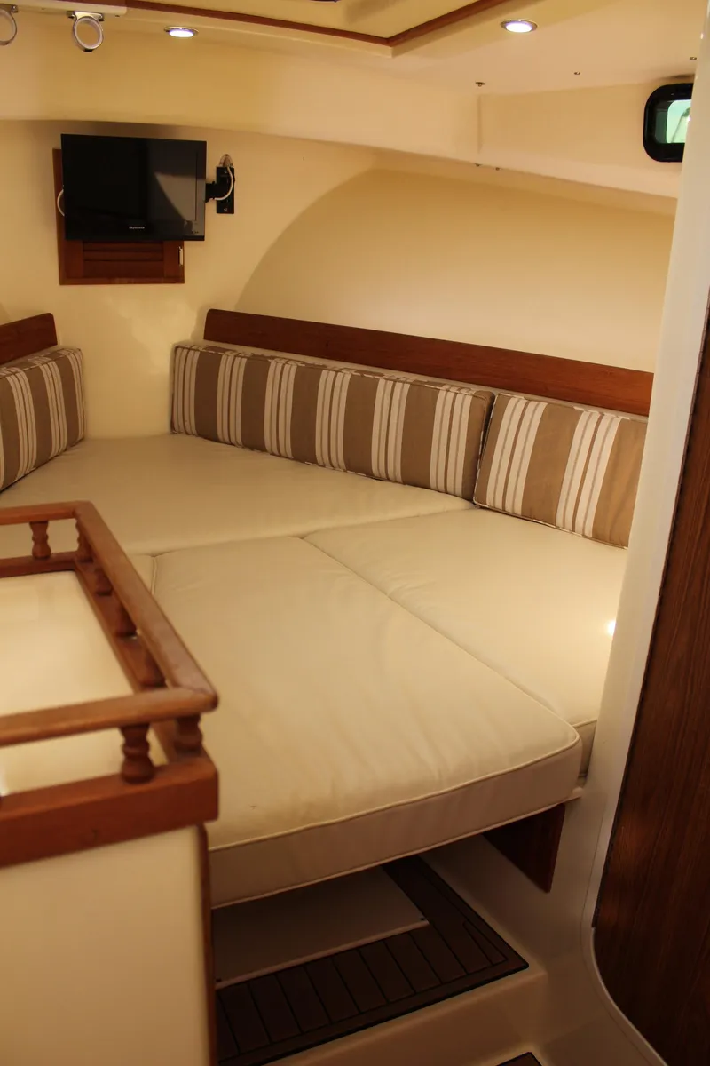 Slide: The Image of Cozy interior of 2016 Eastern 27' Islander boat with striped cushions and mounted TV. - 25