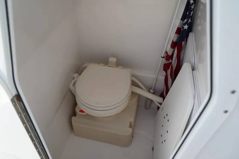 Slide: The Image of 2014 Edgewater 245CC boat interior with compact marine toilet and American flag. - 37