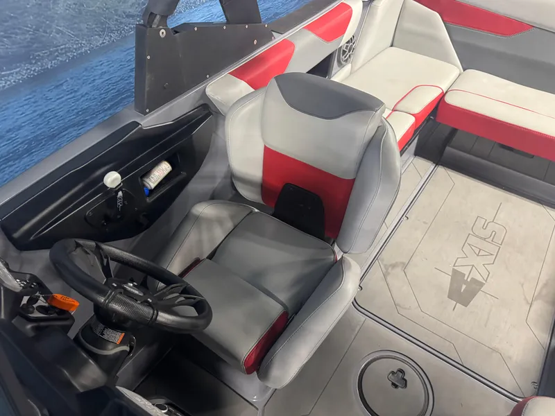 Slide: The Image of 2021 Axis A22 boat interior with red and gray seating, steering wheel, and dashboard. - 13