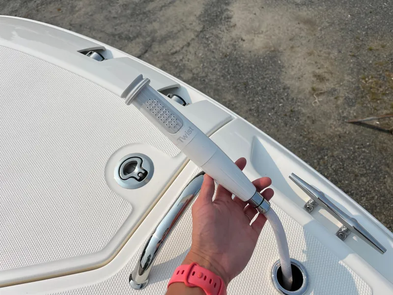 Slide: The Image of Hand holding a hose on a 2025 Boston Whaler 330 Vantage boat deck. - 12