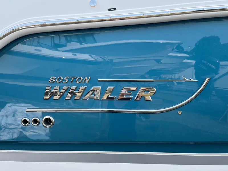 Slide: The Image of 2025 Boston Whaler 330 Vantage boat logo on blue hull. - 40
