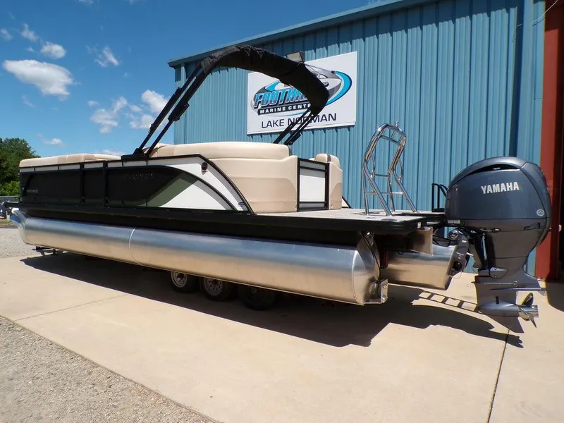 Slide: The Image of 2025 Godfrey Sweetwater 2286 SB pontoon boat with Yamaha motor, parked outside a blue building. - 17