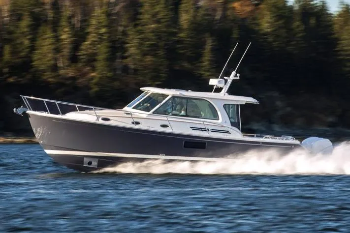Slide: The Image of 2026 Back Cove 39O cruising on water with forested shoreline in background. - 1