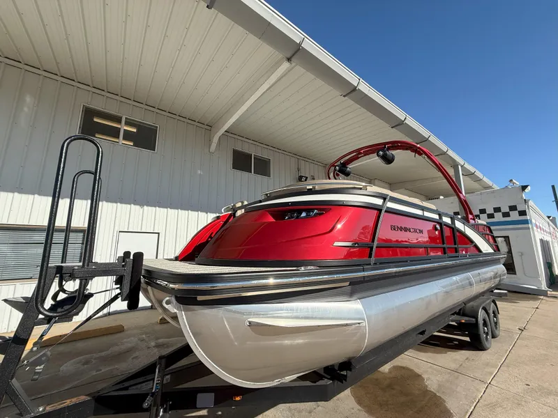 Slide: The Image of 2025 Bennington 25QXFB pontoon boat in vibrant red, parked on a trailer. - 1