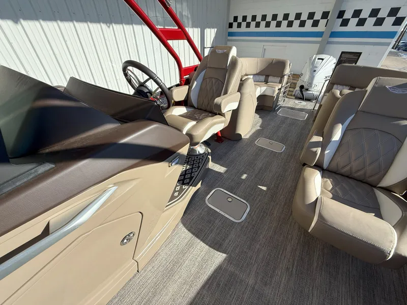 Slide: The Image of 2025 Bennington 25QXFB boat interior with beige seating and modern steering console. - 11