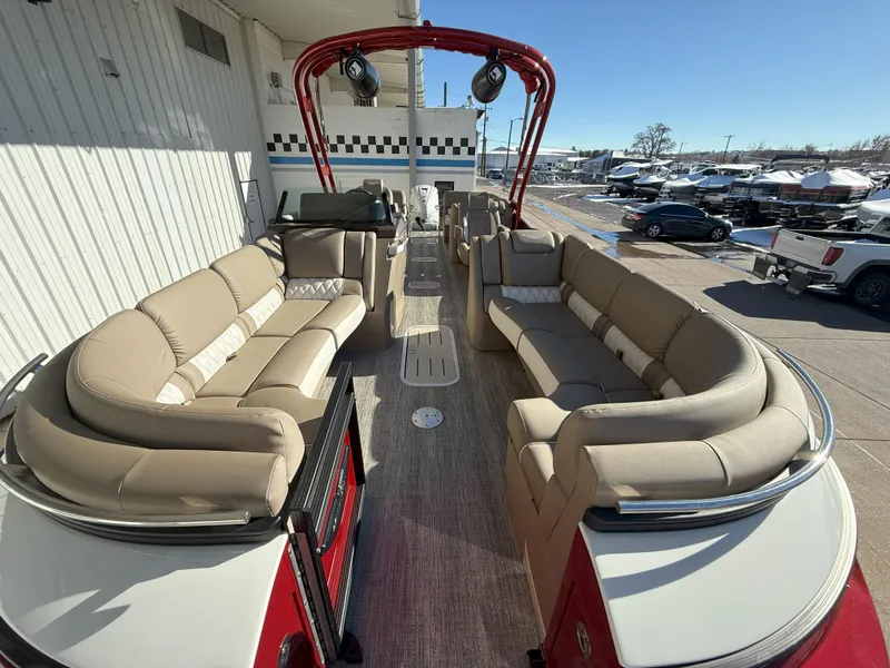Slide: The Image of 2025 Bennington 25QXFB pontoon boat with spacious seating and modern design at a marina. - 6