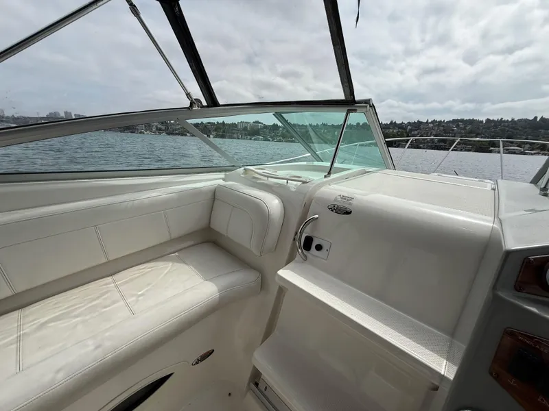 Slide: The Image of 2010 Bayliner 255 SB boat interior with white seating, overlooking a calm lake. - 10