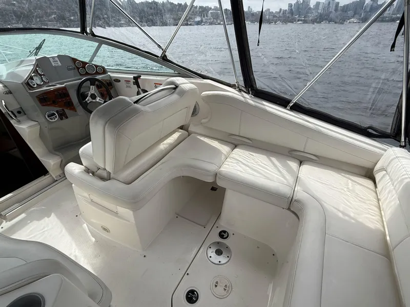 Slide: The Image of 2010 Bayliner 255 SB boat interior with white seating and dashboard, overlooking water and city skyline. - 13