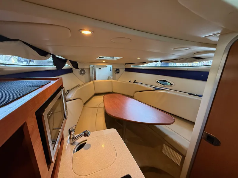 Slide: The Image of 2010 Bayliner 255 SB cabin interior with seating, table, and kitchenette. - 15