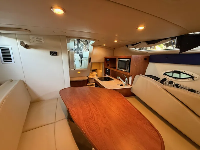 Slide: The Image of Interior of 2010 Bayliner 255 SB boat with kitchen, seating, and wooden table. - 16