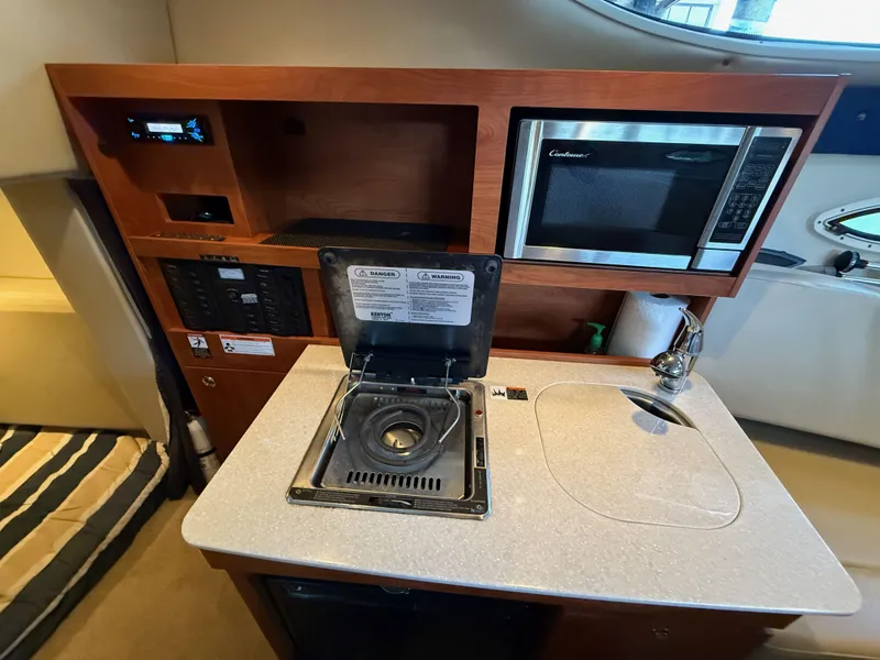 Slide: The Image of 2010 Bayliner 255 SB interior kitchen with stove, sink, and microwave. - 18