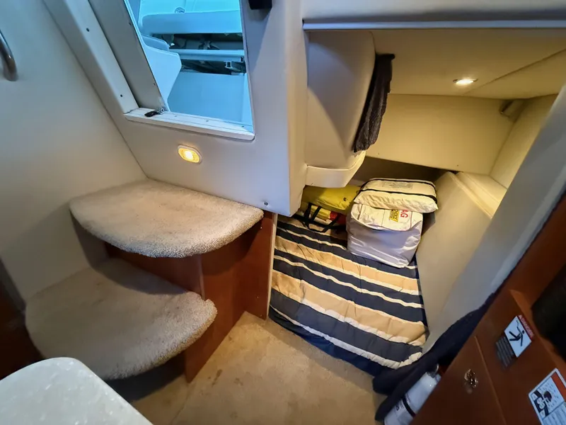 Slide: The Image of Interior cabin of 2010 Bayliner 255 SB boat with carpeted steps and cozy sleeping area. - 20