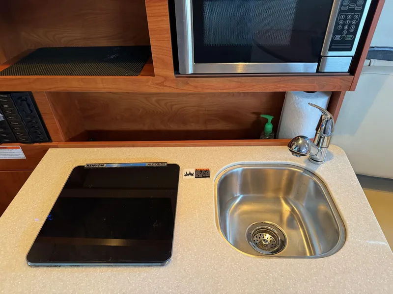Slide: The Image of Compact kitchen area in a 2010 Bayliner 255 SB boat with sink and microwave. - 21