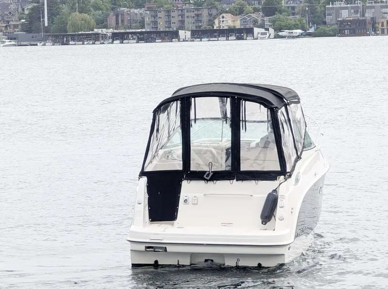 Slide: The Image of 2010 Bayliner 255 SB boat on a calm lake with cityscape background. - 3