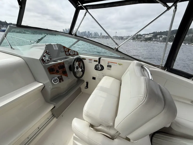 Slide: The Image of 2010 Bayliner 255 SB boat interior with steering wheel, white seating, and city skyline view. - 5