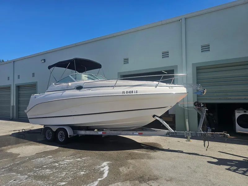 Slide: The Image of 2002 Rinker 242 Fiesta Vee boat on trailer, parked outside storage units. - 0
