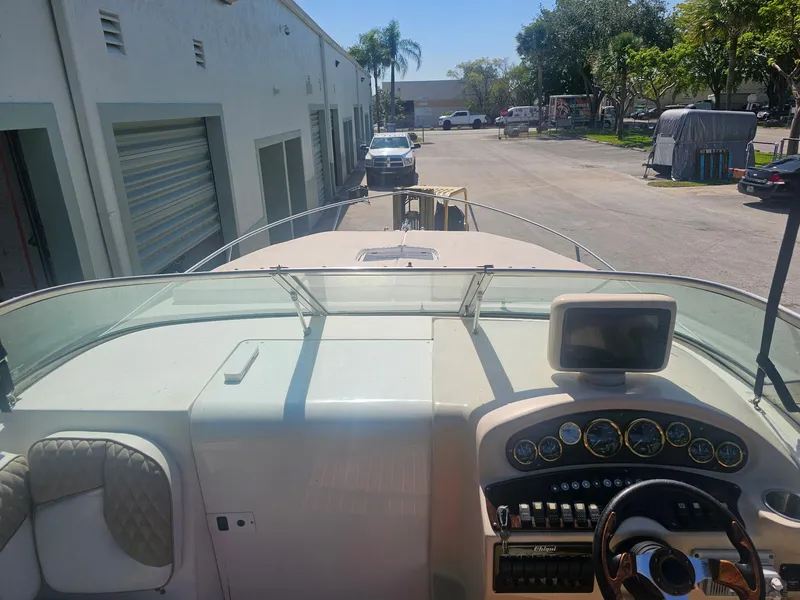 Slide: The Image of 2002 Rinker 242 Fiesta Vee boat dashboard with steering wheel and gauges in a sunny outdoor setting. - 2