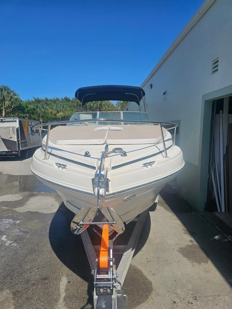 Slide: The Image of 2002 Rinker 242 Fiesta Vee boat on trailer, parked outdoors under clear blue sky. - 3