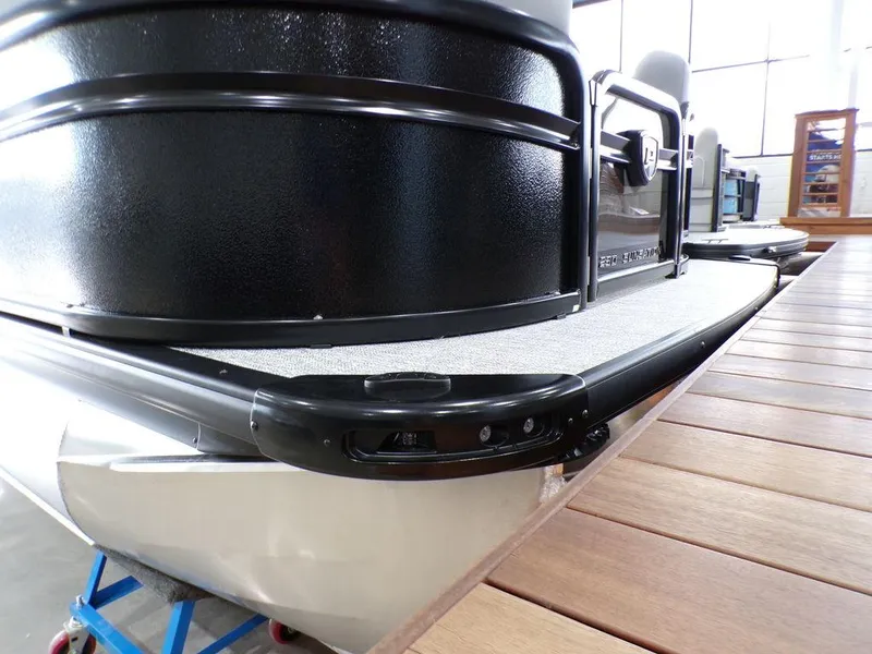 Slide: The Image of 2025 Premier 230 Sunsation RL pontoon boat, black exterior, docked indoors. - 22