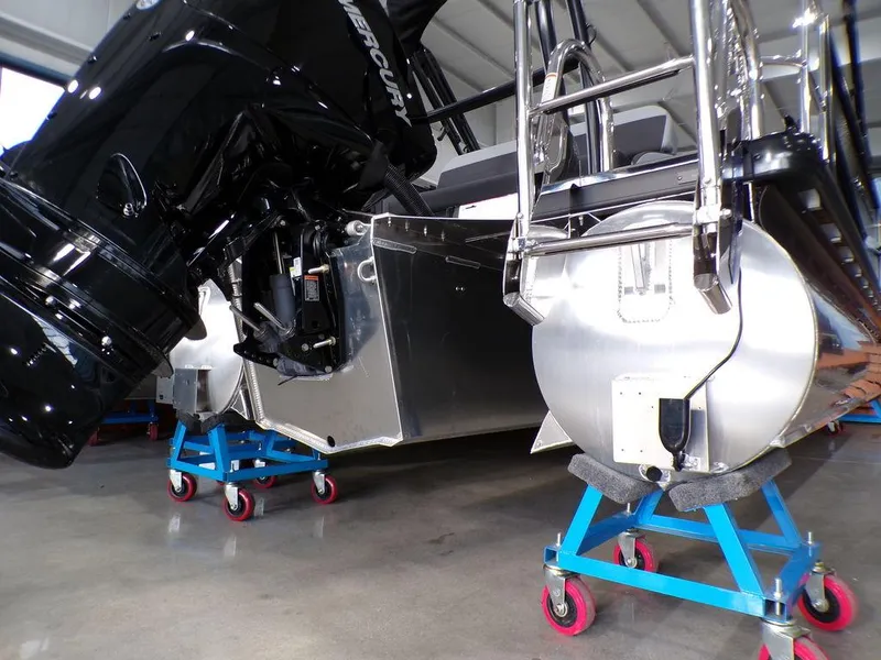 Slide: The Image of 2025 Premier 230 Sunsation RL pontoon boat on stands, showcasing engine and pontoons. - 24