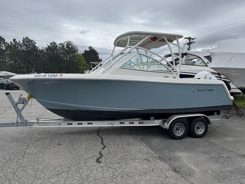 Slide: The Image of 2023 Sailfish 245 DC boat on trailer, parked outdoors under cloudy sky. - 1