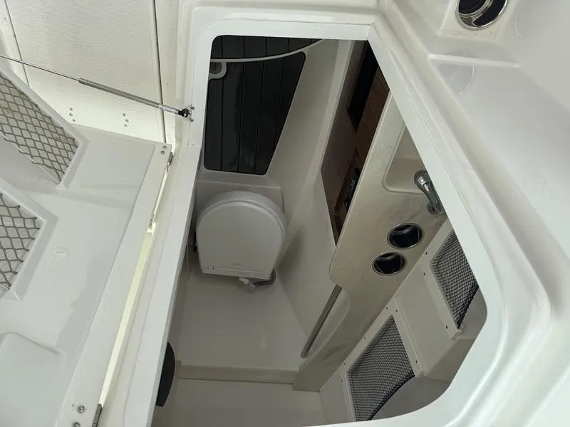 Slide: The Image of 2023 Sailfish 245 DC boat interior with compact toilet and storage compartments. - 10