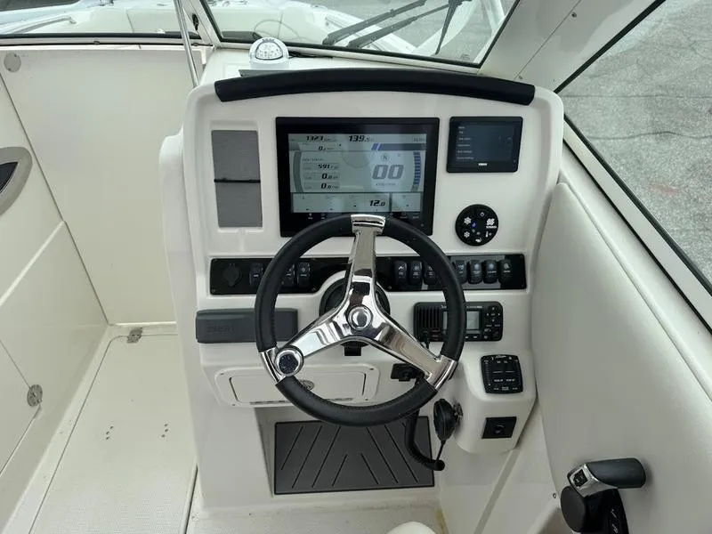 Slide: The Image of 2023 Sailfish 245 DC boat dashboard with steering wheel and digital display. - 6