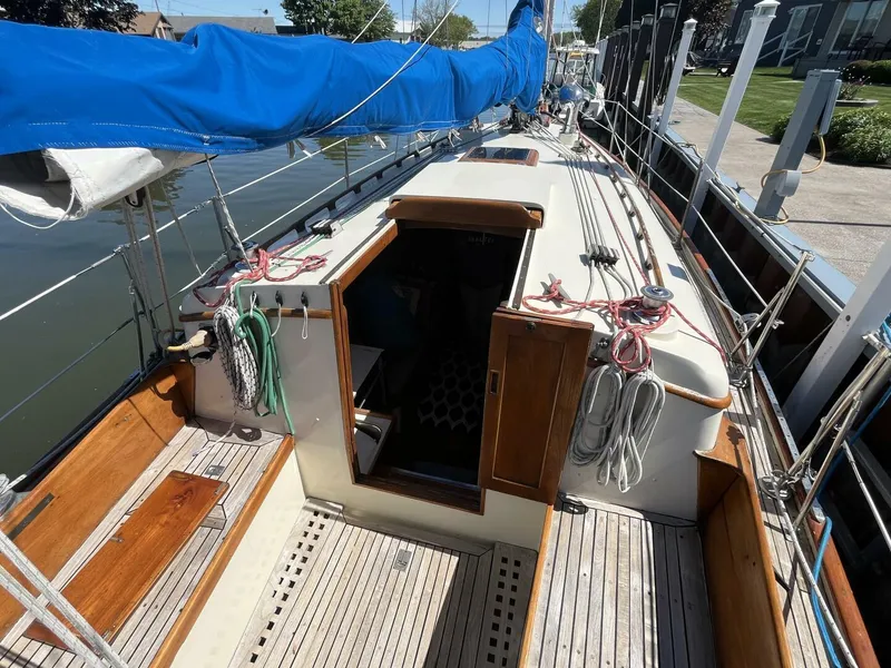 Slide: The Image of 1978 Cheoy Lee Offshore 33 sailboat with blue sail cover, docked, showing deck and cabin entrance. - 12