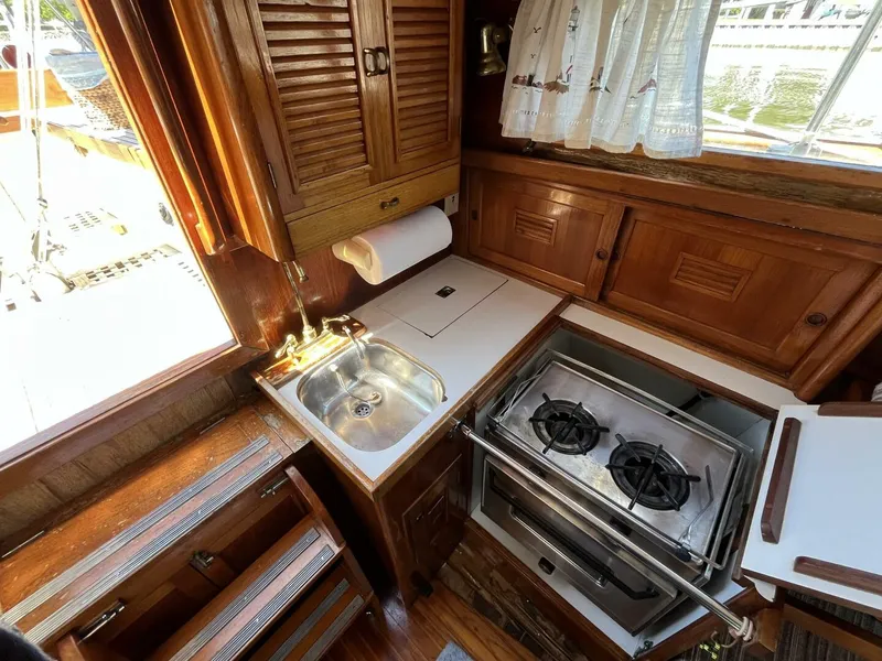 Slide: The Image of 1978 Cheoy Lee Offshore 33 yacht kitchen with stove, sink, and wooden cabinetry. - 31