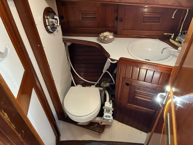 Slide: The Image of 1978 Cheoy Lee Offshore 33 yacht bathroom with wooden cabinetry and compact marine toilet. - 37