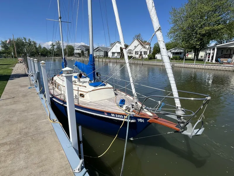 Slide: The Image of 1978 Cheoy Lee Offshore 33 sailboat docked in a serene canal setting. - 7