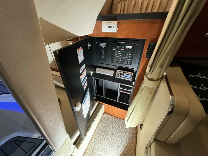 Slide: The Image of 2007 Sea Ray 280 Sundancer interior control panel with open cabinet and beige upholstery. - 47