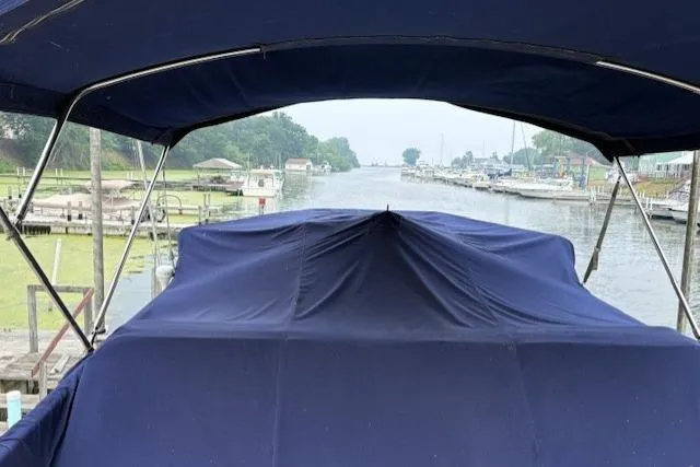 Slide: The Image of 1978 Grand Banks 36 Classic boat with blue cover, docked by a scenic river. - 19