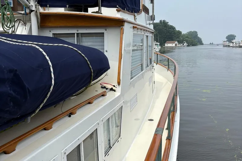 Slide: The Image of 1978 Grand Banks 36 Classic yacht on a calm river, showcasing its deck and railing. - 24