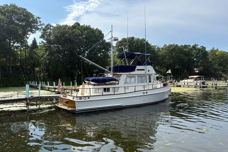 Slide: The Image of 1978 Grand Banks 36 Classic yacht docked on a serene lake with lush greenery. - 28