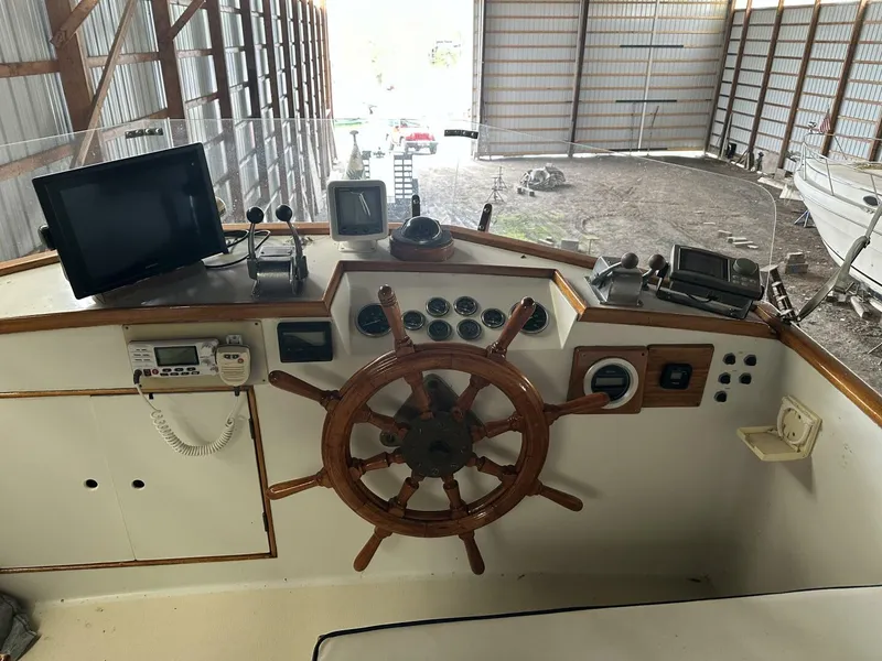 Slide: The Image of 1978 Grand Banks 36 Classic helm with wooden wheel and navigation instruments in a boat shed. - 6