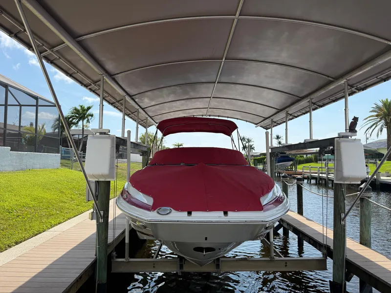 Slide: The Image of 2019 Crownline Eclipse E255 XS boat with red cover on a lift under a canopy. - 0