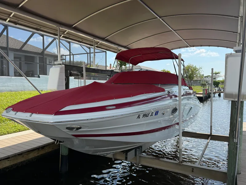 Slide: The Image of 2019 Crownline Eclipse E255 XS boat with red cover on a lift under a canopy. - 1