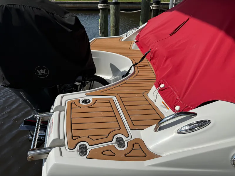 Slide: The Image of 2019 Crownline Eclipse E255 XS boat with red cover and teak deck at dock. - 2
