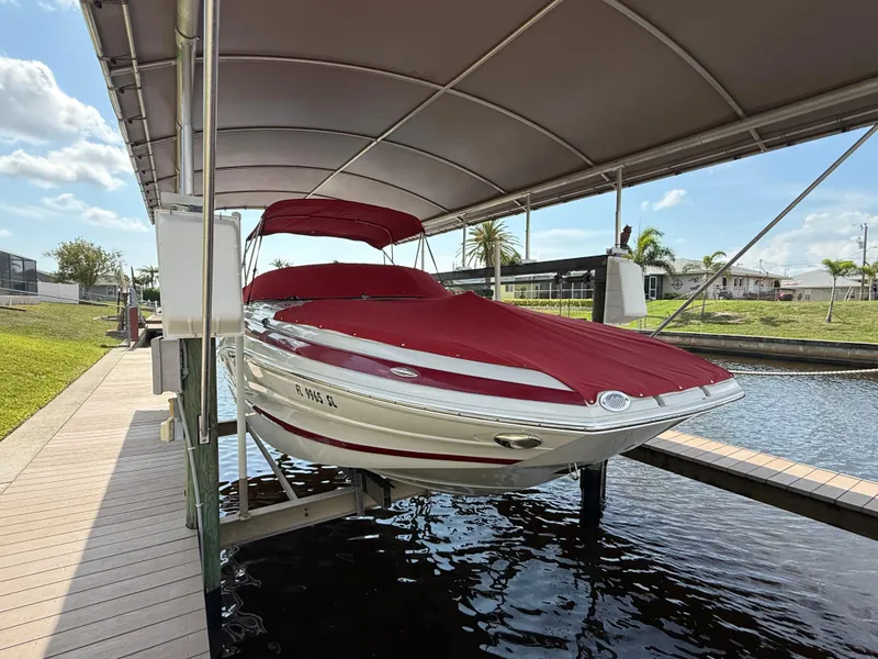 Slide: The Image of 2019 Crownline Eclipse E255 XS boat with red cover on a lift, under canopy. - 3